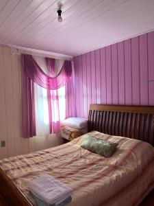 Un dormitorio con una cama con paredes rosas y una ventana en Orange House Canela, en Canela