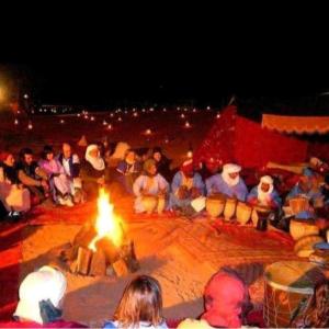 un grupo de personas están sentados alrededor de un fuego en Desert Berber Fire-Camp en Merzouga