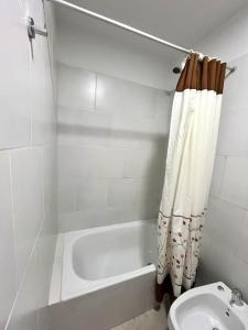 uma casa de banho com uma banheira, um WC e uma cortina de chuveiro. em Alojamiento confortable para tus días en Córdoba. em Córdoba