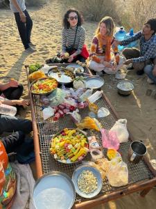 un grupo de personas sentadas alrededor de una mesa con comida en Hostel Desert Home Stay, en Jaisalmer