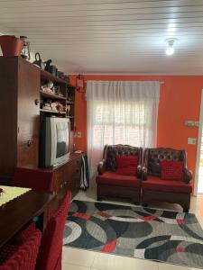 Una sala de estar con un sofá y un televisor. en Orange House Canela, en Canela