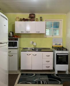 una cocina con armarios blancos y fregadero en Orange House Canela, en Canela