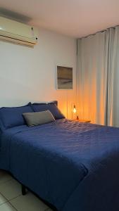 a large blue bed in a room with a lamp at Macarena Flat Praia ap 109 in Natal