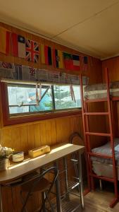 a room with a table and a bunk bed and a window at CABAÑA EL BUHO - ESMERALDA in Puerto Natales