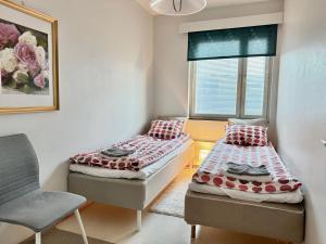 2 Betten in einem Zimmer mit einem Stuhl und einem Fenster in der Unterkunft Joensuu keskustaneliö in Joensuu