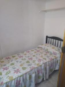ein Schlafzimmer mit einem Bett mit geblümter Bettdecke in der Unterkunft Depto frente a Shopping Aldrey in Mar del Plata