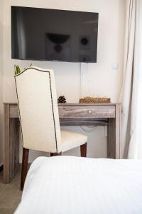 a chair in front of a desk with a television at Coastal Elegance Suite 1-Min to the Beach in Ampavris