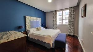 sypialnia z niebieskimi ścianami, łóżkiem i oknem w obiekcie Moreno 820 Design Apartments w BuenosAires