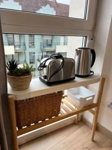 ein Fensterbrett mit einem Toaster, einem Toaster und einem Korb in der Unterkunft Adorable Appartement Strasbourg NEUDORF PARKING SOUS SOL in Straßburg