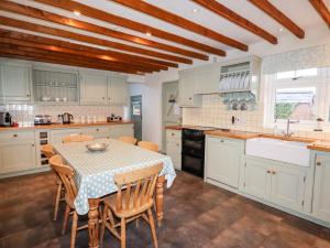 a kitchen with a table and chairs and a kitchen with white cabinets at Plas Cwtta in Clocaenog