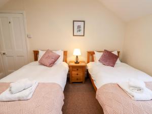 a bedroom with two beds and a lamp on a night stand at Plas Cwtta in Clocaenog