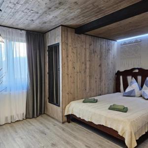 a bedroom with a bed with wooden walls and a window at Садиба "333" in Yaremche