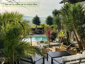 a patio with a table and a pool with palm trees at Villa Merkel - 28 pers - 11 chambr - 10 WC - Piscine in Anglet