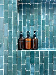 three bottles of soap on a green tiled wall at Blue Sunday, Desert House w/ hot tub -Joshua Tree in Joshua Tree