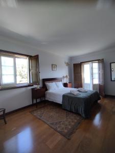 a bedroom with a bed and two windows at Casa Maria Joana in Ponte de Lima