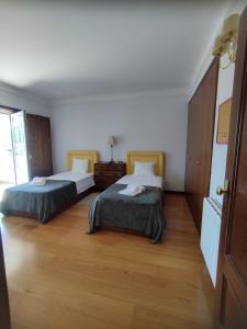 two beds in a room with wooden floors at Casa Maria Joana in Ponte de Lima