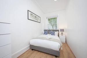 a white bedroom with a bed and a window at 2 Bed Piccadilly Apartment- 3 in London