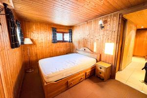 a small bedroom with a bed in a wooden room at Snowflake cottage with garden in Chamonix