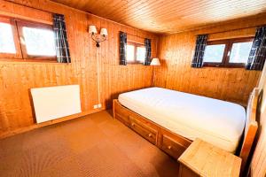 夏慕尼白朗峰的住宿－Snowflake cottage with garden，一间小卧室,配有一张位于木制房间内的床