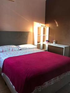 1 dormitorio con 1 cama grande con manta rosa en Pousada da Lua, en Rolante