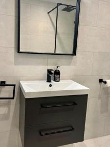 a bathroom with a white sink and a mirror at Chic, Relaxing stay just 18 mins into the City in London