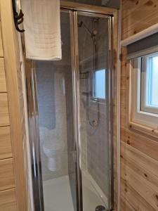 a shower with a glass door in a bathroom at Rowan Gorgeous Glamping Hideaway in Durnamuck