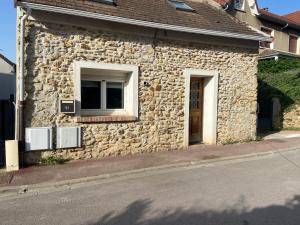 a stone building with a window on a street at Maison au calme a l'orée du bois. Accès A13-A14 in Orgeval