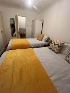 two beds in a room with yellow sheets at Princess Wigan House in Wigan