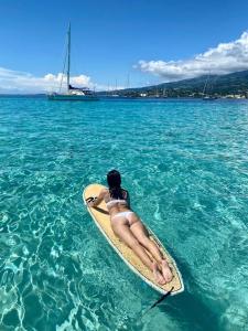 une femme en bikini posant sur une planche de surf dans l'eau dans l'établissement Tahiti Private Catamaran, à Uturoa