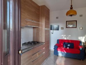 uma cozinha com um sofá vermelho e um fogão em 8380 Morellino little house em Montemerano
