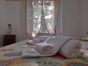 uma pilha de toalhas numa cama com uma janela em 8380 Morellino little house em Montemerano