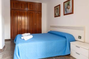Un dormitorio con una cama azul con toallas. en Suitur apartament familiar con piscina calafell, en Calafell