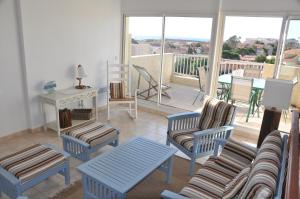 sala de estar con sillas, mesa y balcón en Arc en ciel, vue mer et piscine dans résidence en Saint Pierre La Mer