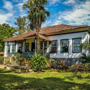 a house with a palm tree in front of it at Fazenda Dos Coqueiros-Bananal-SP in Bananal