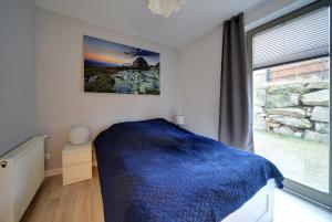 Un dormitorio con una cama azul y una ventana en Mocca apartament z dwoma sypialniami i tarasem en Szklarska Poręba