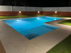 una gran piscina de agua azul por la noche en Masia Casa Roja, en Banyeres del Penedés