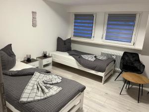 1 dormitorio con 2 camas, silla y ventanas en Ferienwohnung, Monteurwohnung, Unterkunft in Warstein NRW, Deutschland en Warstein