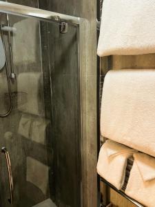 a shower with a glass door next to some towels at Maple Bank Country Guest House in Keswick