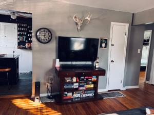 a living room with a flat screen tv and a clock at 10 min Downtown-3 min Irvington in Indianapolis