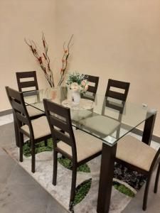 a glass dining room table with chairs and a vase with flowers at RESIDENCE E.P in Emana