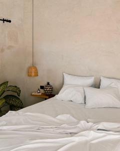 uma cama com lençóis brancos e almofadas num quarto em Tukasa - Surfhouse Popoyo em Popoyo