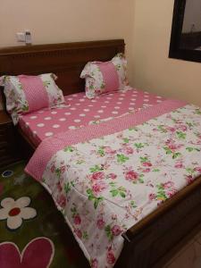 a bed with a pink and white comforter on it at RESIDENCE E.P in Emana