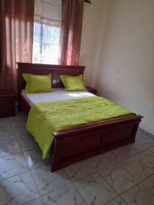 a bedroom with a bed with a green comforter and a window at RESIDENCE E.P in Emana