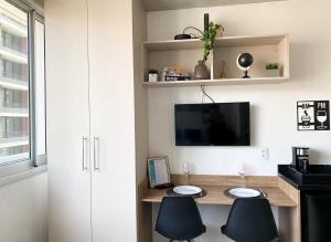 Habitación con escritorio con 2 sillas y TV. en Charming Frei Caneca, en São Paulo