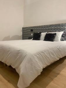 a large white bed with black pillows on it at cosy apart hotel 1st in Calais