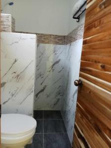 a bathroom with a toilet and a shower at Vali-Joe Travel Lodge in El Nido