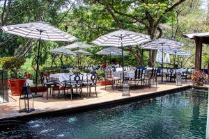 a group of tables and chairs with umbrellas next to a pool at Il Piccolo Peccato in Cuernavaca