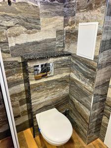 een badkamer met een toilet en een stenen muur bij Azurro Residence in Sofia