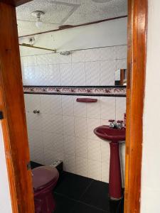 baño con aseo rojo y lavamanos en Casa Campestre Adela en Suesca