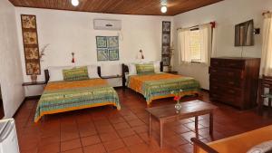 a room with two beds and a table at Pousada Casa da Edinha in Ilha de Boipeba